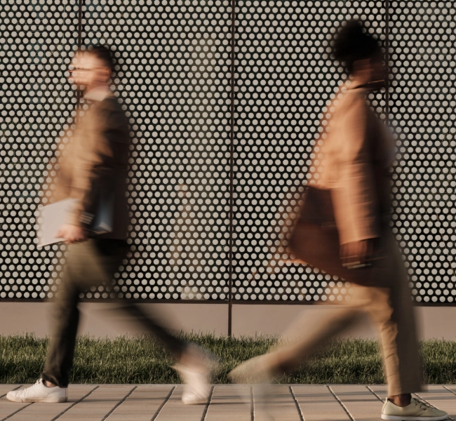 Two people passing each other on the street, their figures blurred.