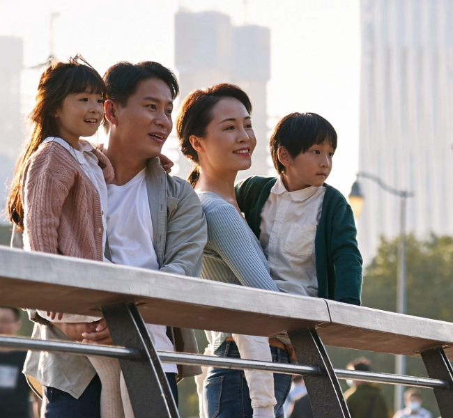 A couple holds their two children while looking at a city building.