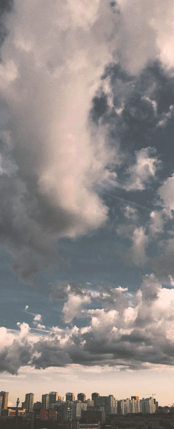 A cloudy blue sky above a city skyline.
