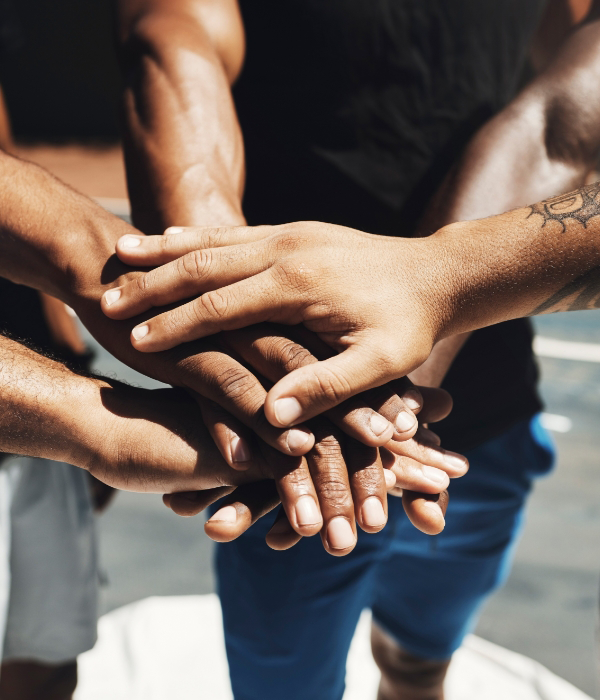 A group of teammates puts their hands together before a big game.
